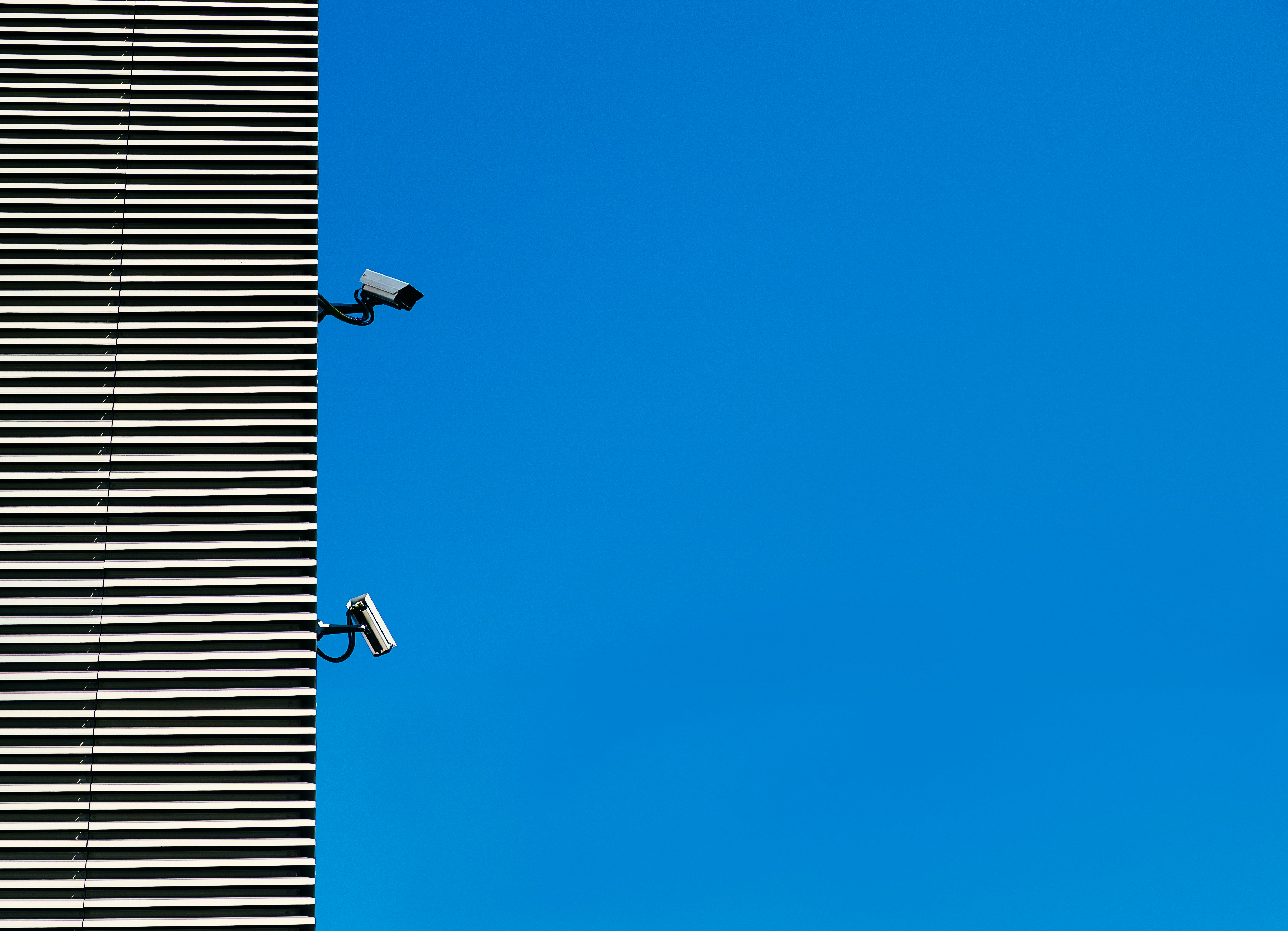 Kamery bezpieczeństwa na tle niebieskiego nieba i nowoczesnego budynku